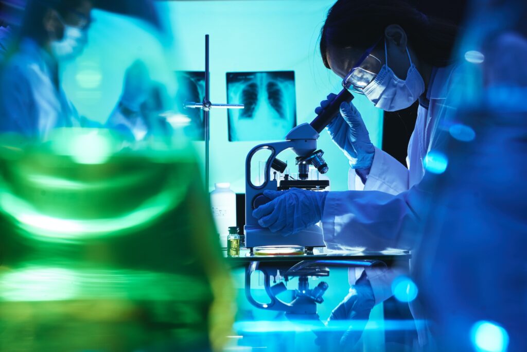 Female cancer research scientist looking in microscope